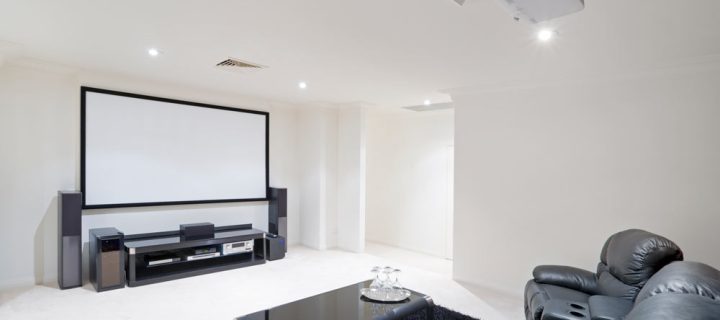 white movie room with black couch, table with glass on top